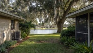 Air Bros HVAC unit installed beside a 1980s Florida ranch home with a screened lanai, mature live oaks draped in Spanish moss, and a calm waterway in the background — Palm Harbor, FL